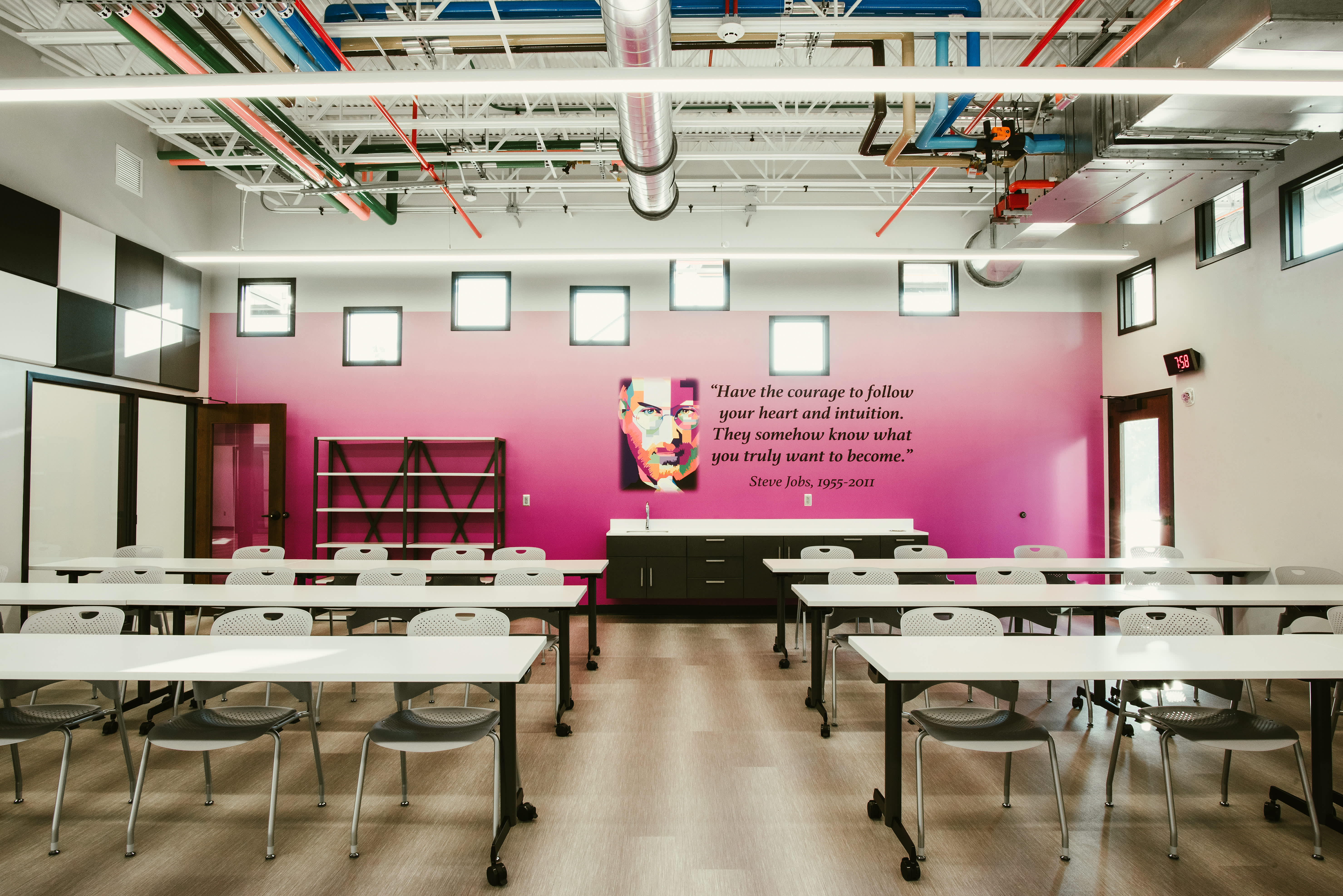 Flexible classroom with mobile tables and an exposed-services ceiling.
