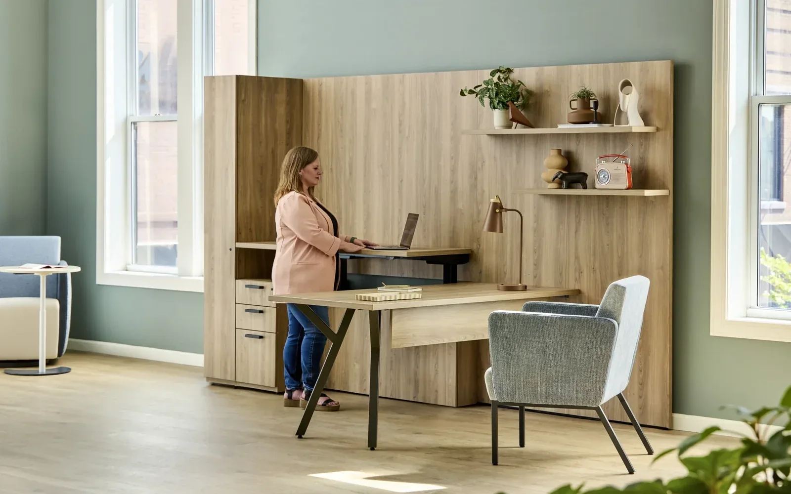 National WaveWorks office with a woman at a raised desk surface, light-wood wall storage, and a gray guest chair