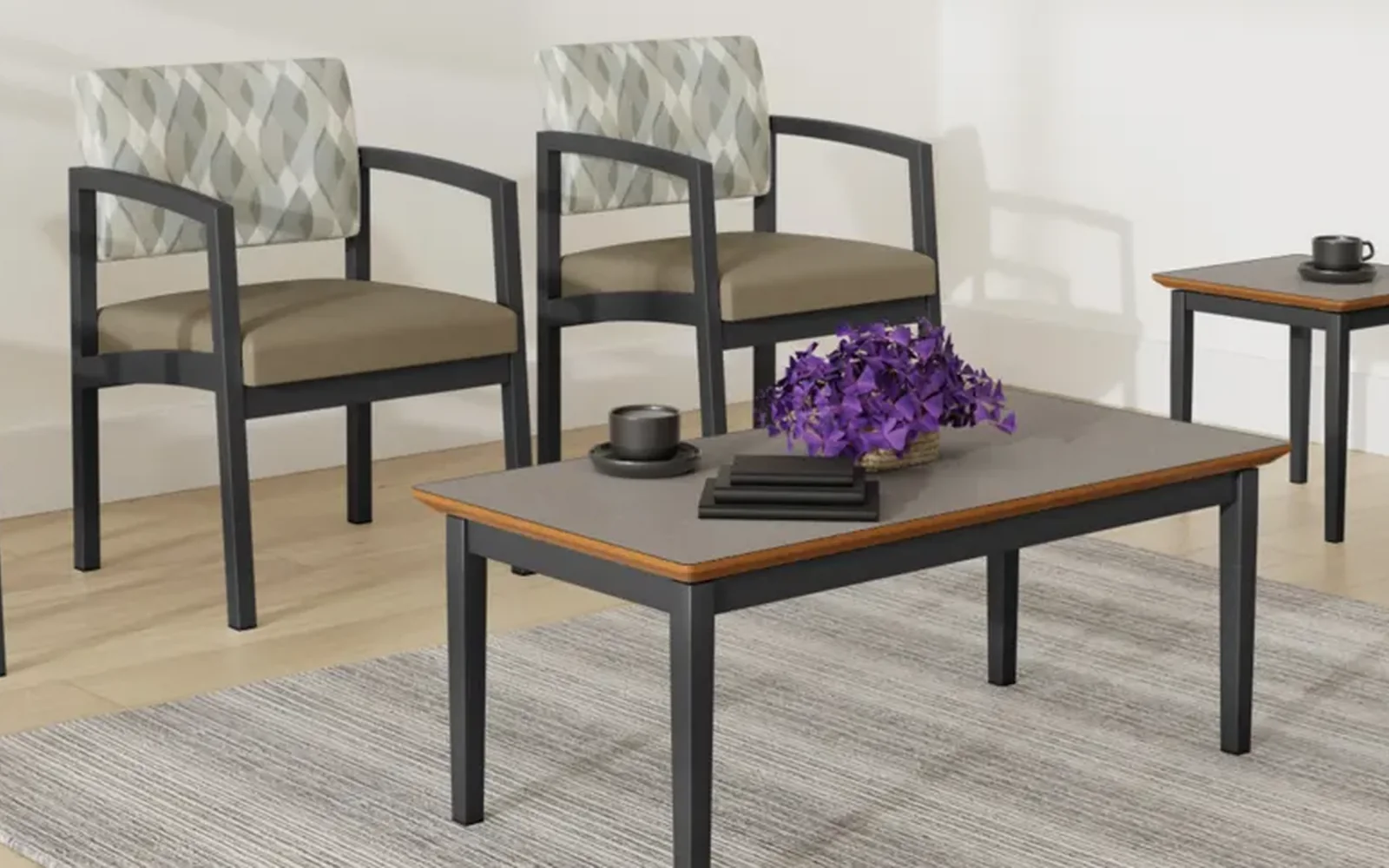 Two patterned Lesro guest chairs with dark metal arms beside matching wood-top tables
